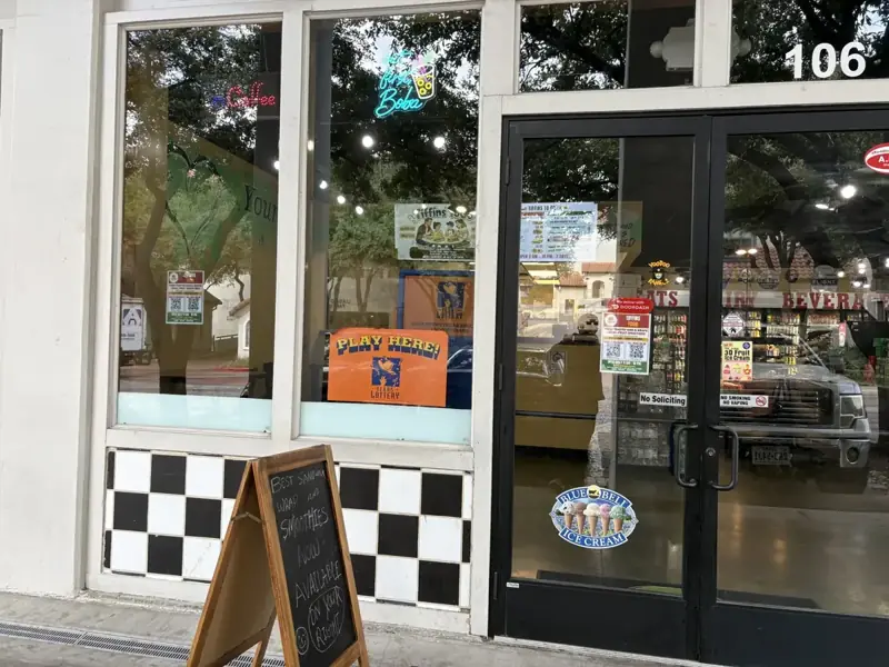 Storefront of Suite 106 on E Las Colinas Blvd in Irving, with a chalkboard sign for sandwiches, wraps and smoothies outside the Urban Center Market doors