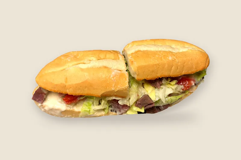 Cheesy Beef Melt on a toasted Italian soft roll, cut in half, with roast beef, melted provolone, tomato and greens