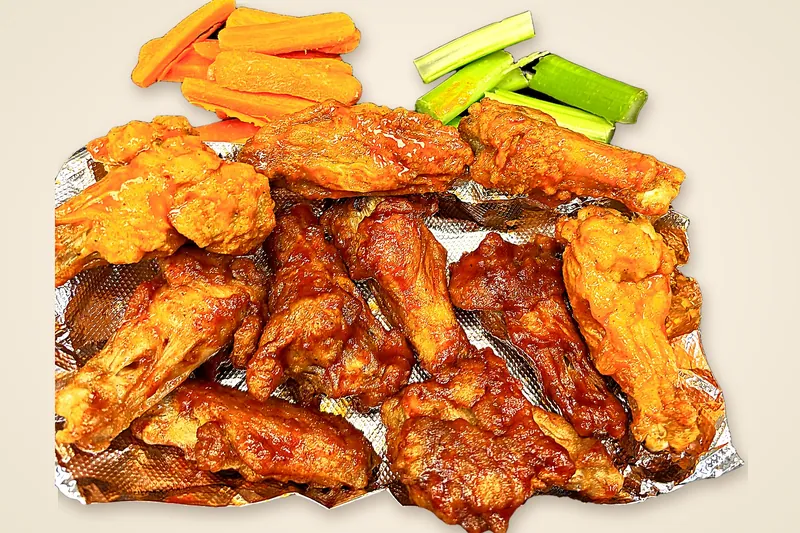 Bone-in chicken wings glazed in Buffalo and BBQ sauce, piled on foil with carrot and celery sticks